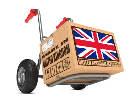 Cardboard Box with Flag of United Kingdom and Made in United Kingdom Slogan on Hand Truck White Background. Free Shipping Concept.