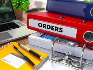 Red Ring Binder with Inscription Orders on Background of Working Table with Office Supplies, Laptop, Reports. Toned Illustration. Business Concept on Blurred Background.-1